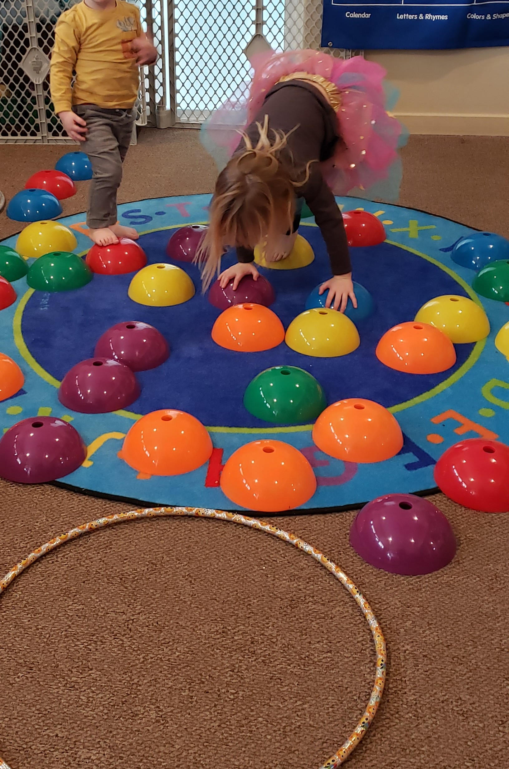 Photo. A little girl balancing on colorful plastic bubbles.