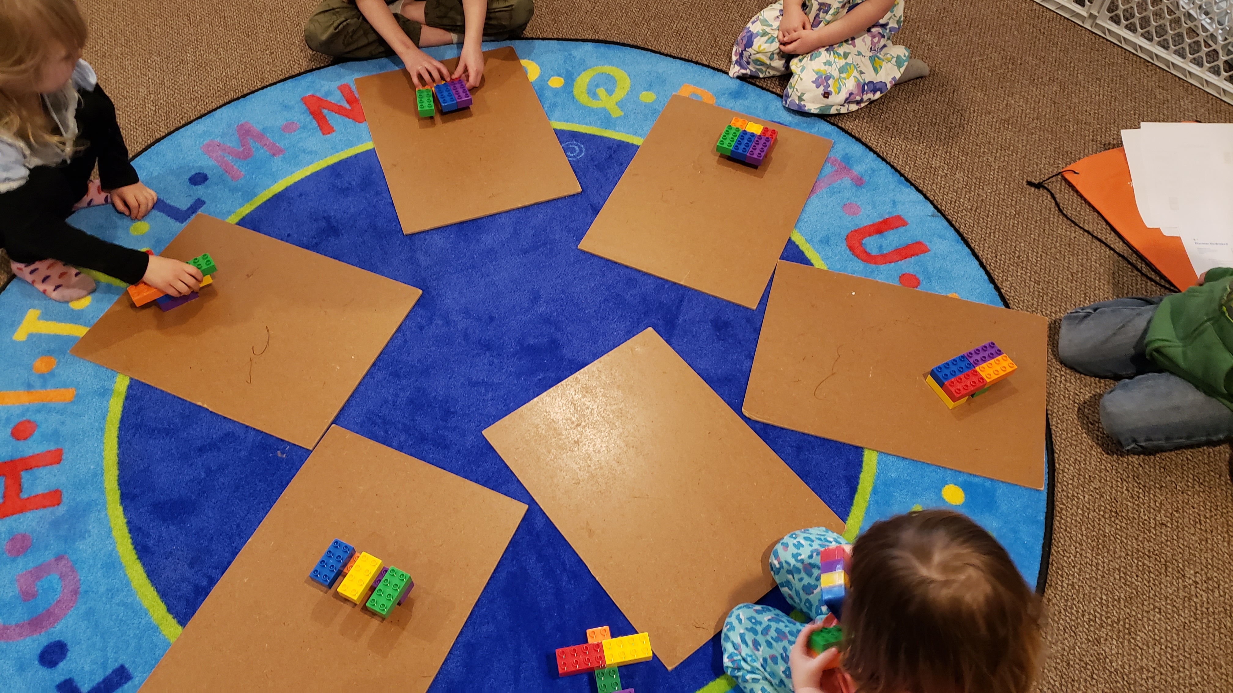 Photo. A circle of children, each playing with their own set of blocks.