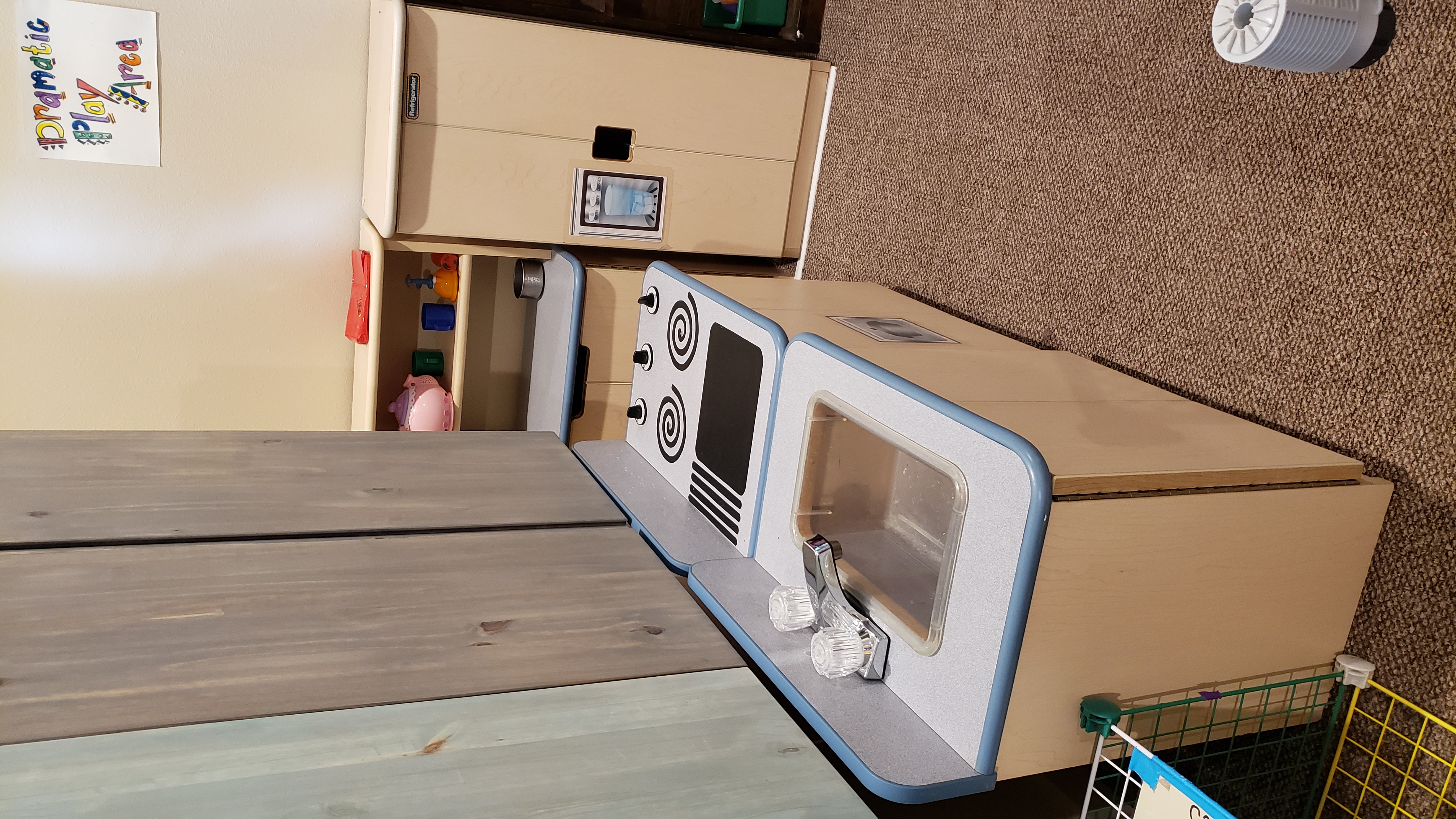 Photo. A play-kitchen, with a toy sink, toy stove, toy refridgerator.